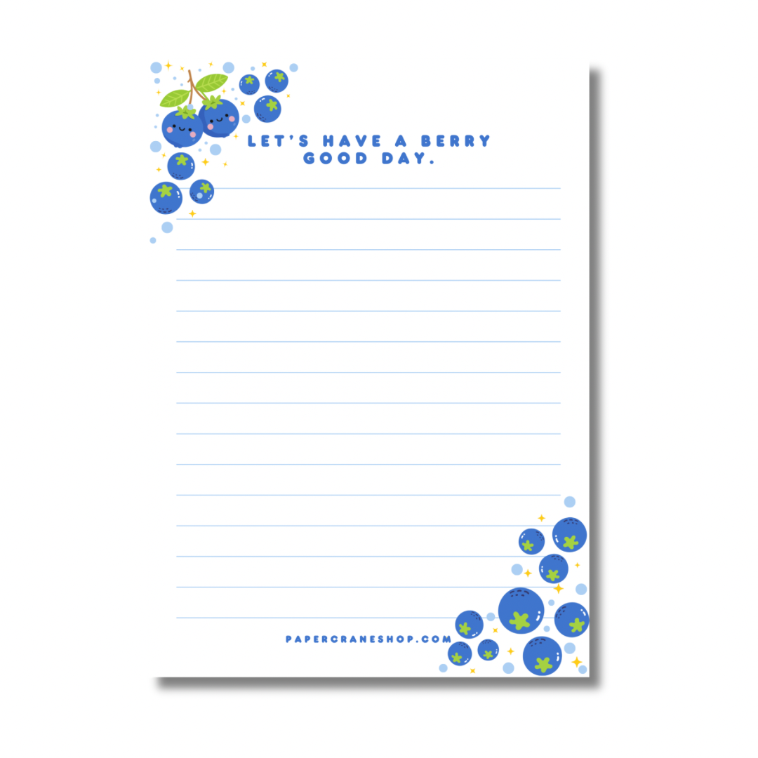 Notepad with blueberry design and text 'Let's have a berry good day.' on a white background.