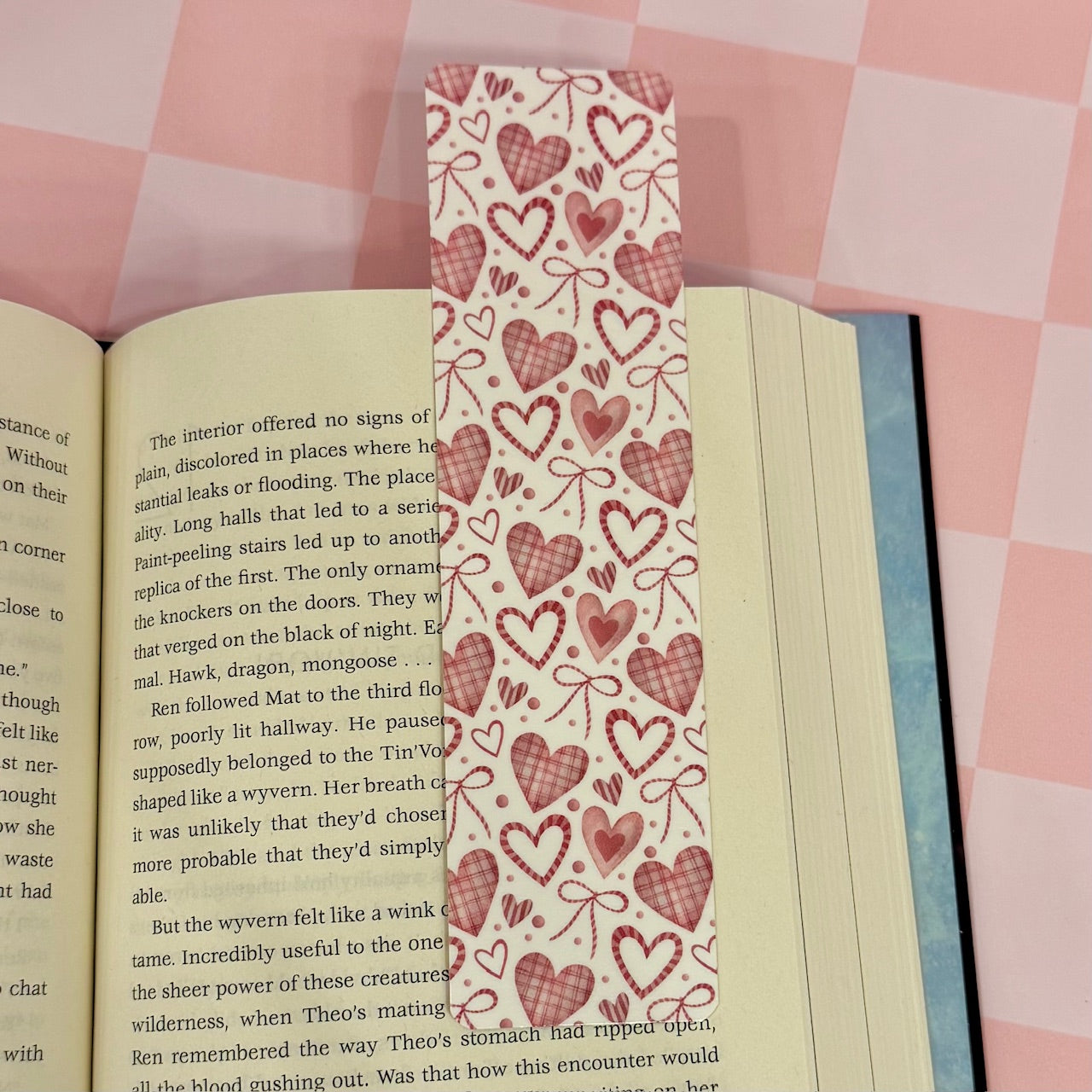 Heart and bow patterned bookmark on an open book with a pink checkered background