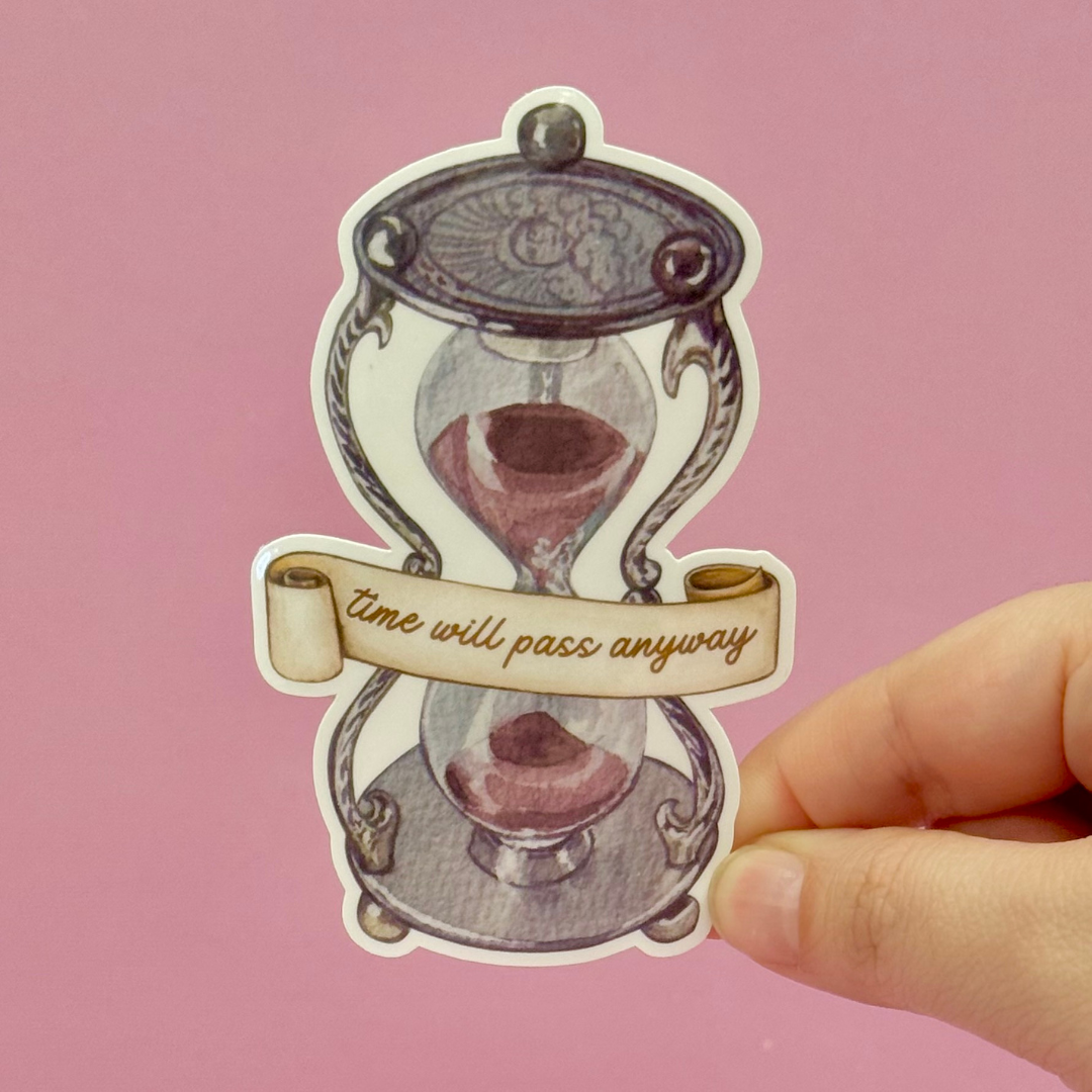 Hourglass sticker with 'time will pass anyway' text held by a hand against a pink background