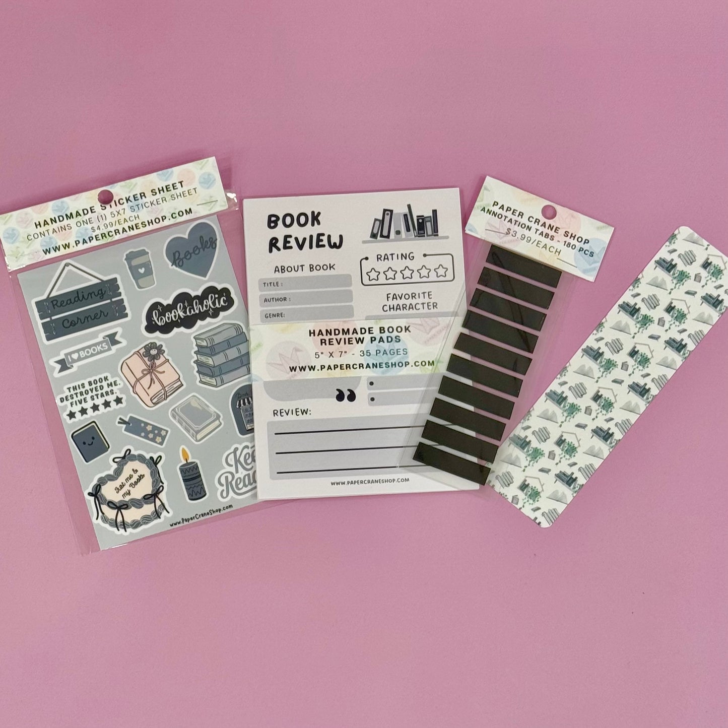 Collection of book-themed stationery items on a pink background
