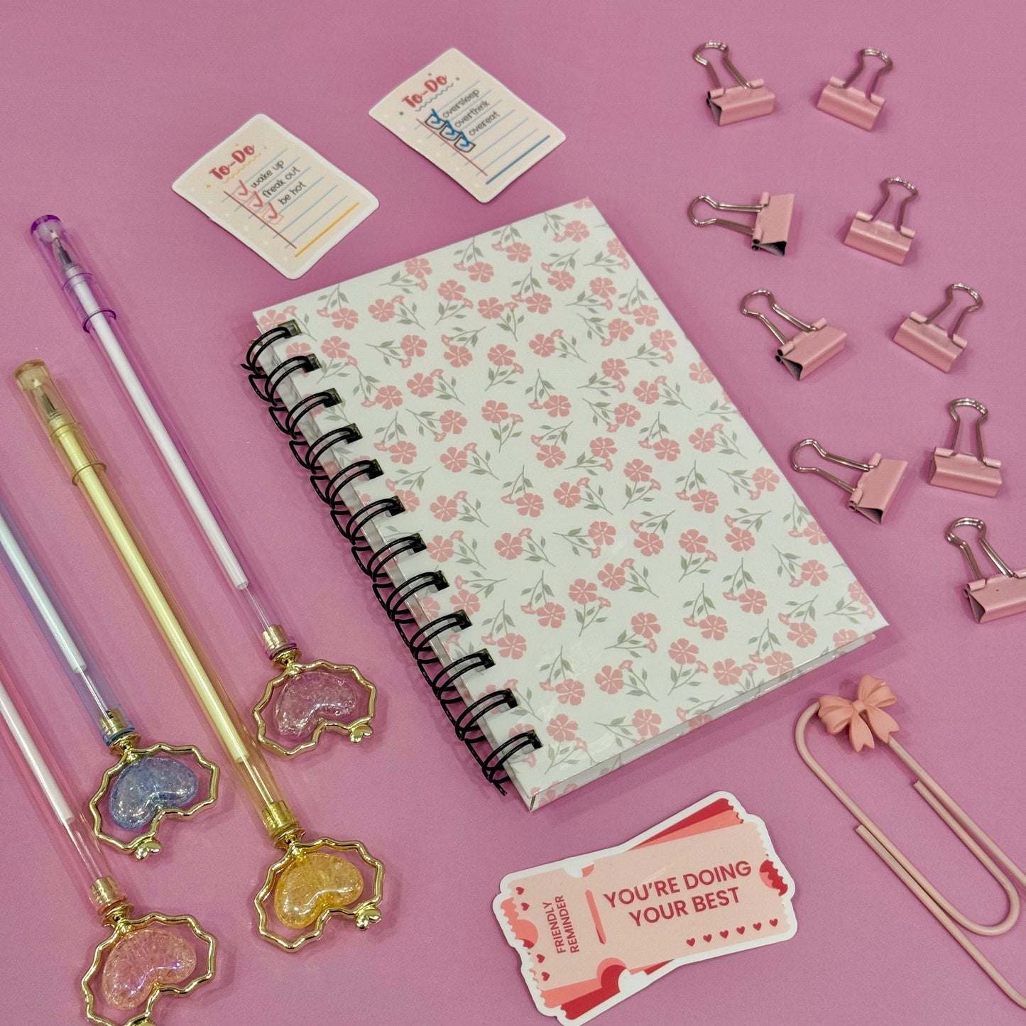 Floral notebook with stationery items on a pink background