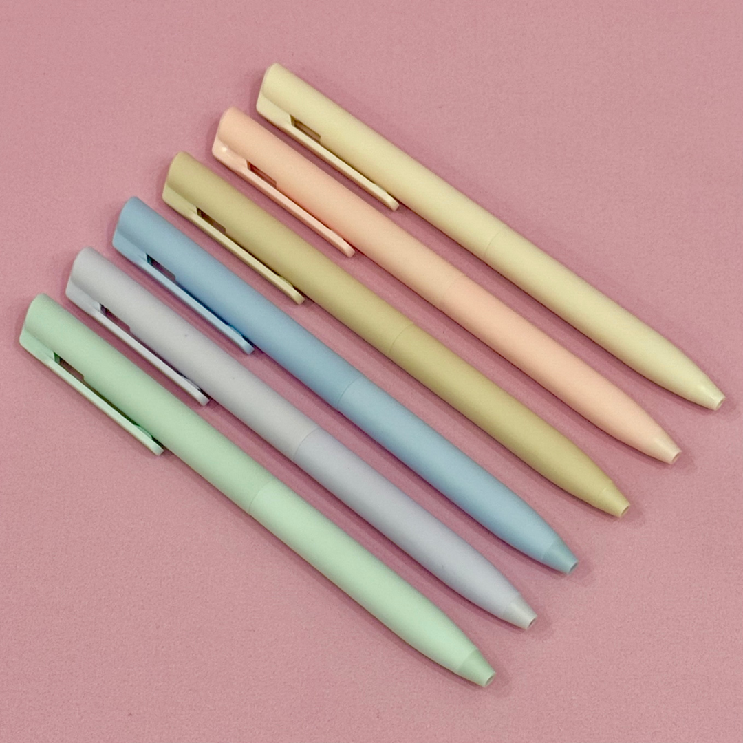 Set of pastel-colored pens on a pink background