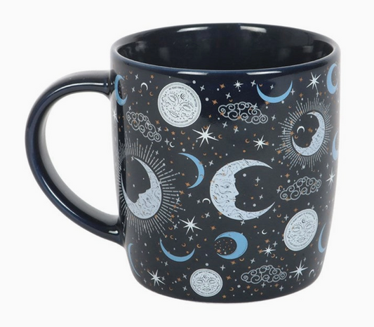 Mug with celestial design featuring moons, stars, and clouds on a dark background
