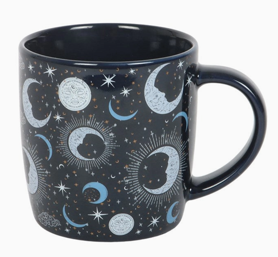 Black mug with celestial pattern featuring moons, stars, and suns on a white background