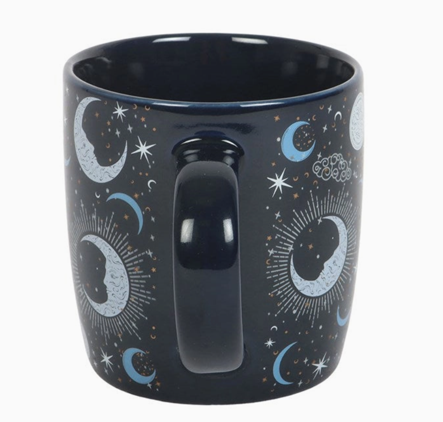 Black mug with celestial design featuring moons, stars, and suns on a white background