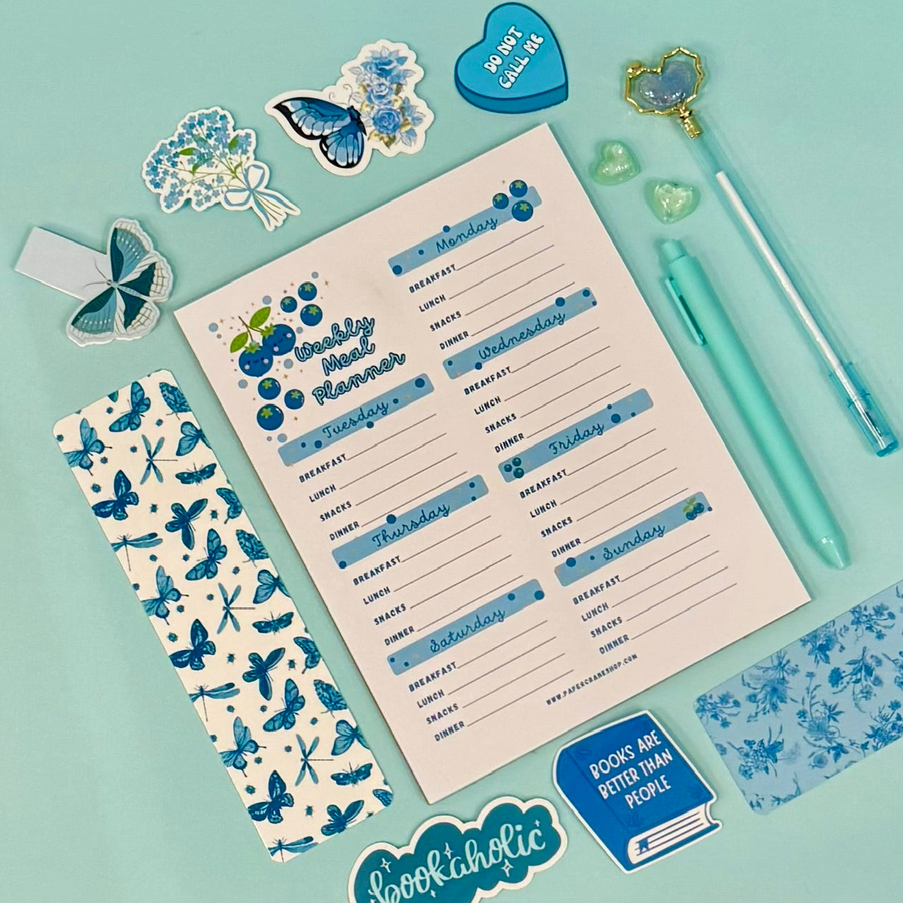 Weekly meal planner with blue blueberries design on a light blue background with stationery items.