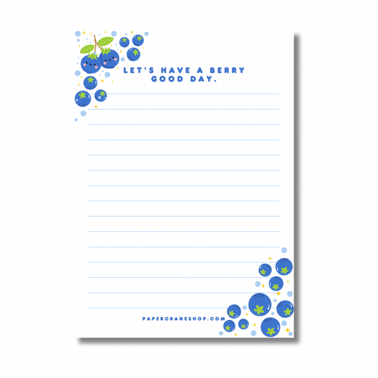 Notepad with blueberry design and text 'Let's have a berry good day.' on a white background.