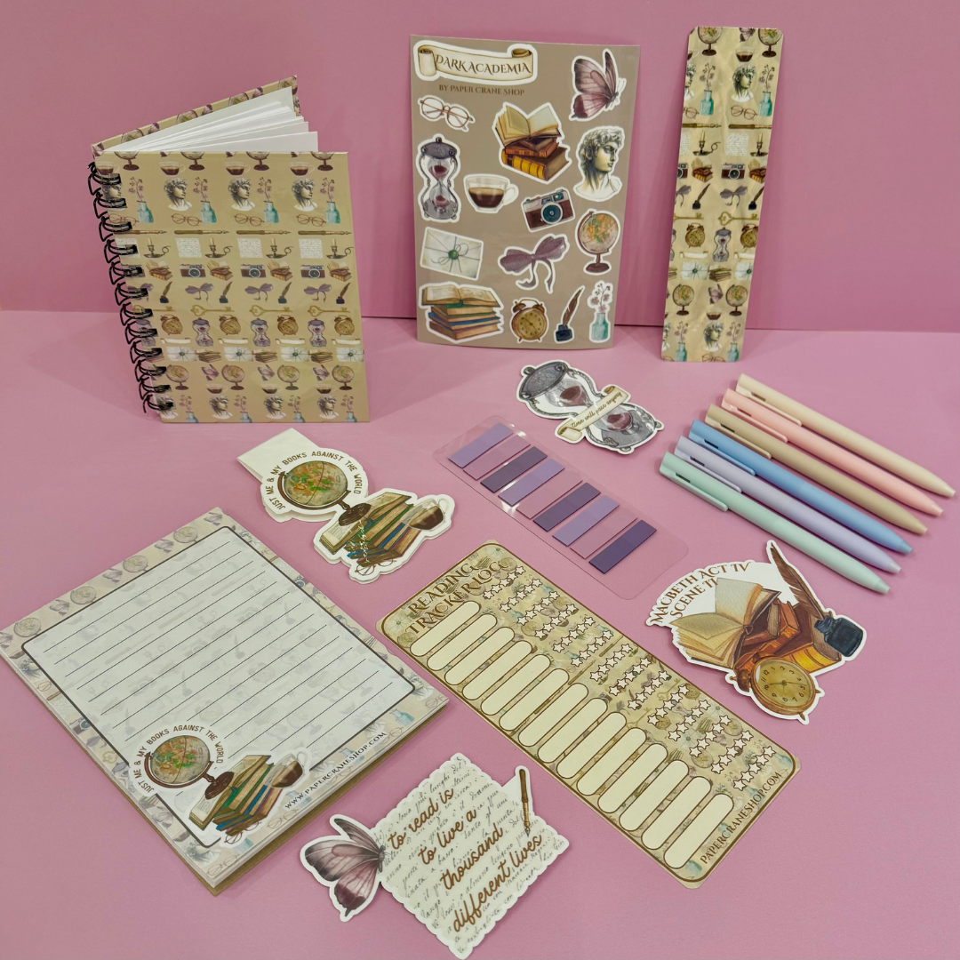 Stationery items including notebooks, stickers, and pens on a pink background