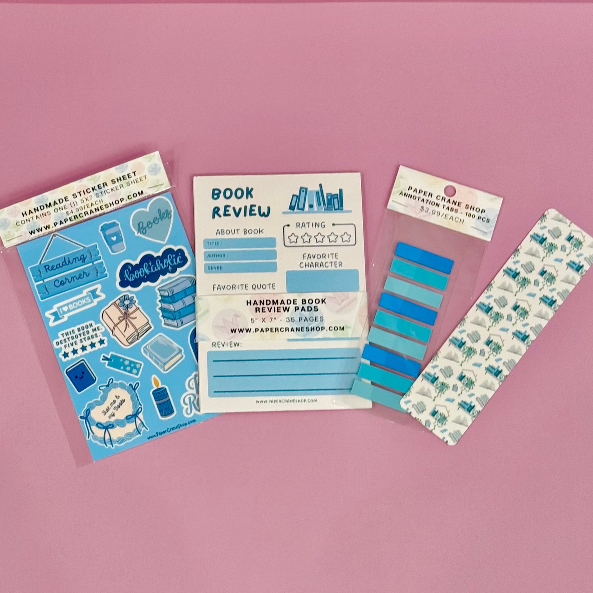 Collection of stationery items including a sticker sheet, book review card, and bookmarks on a pink background.