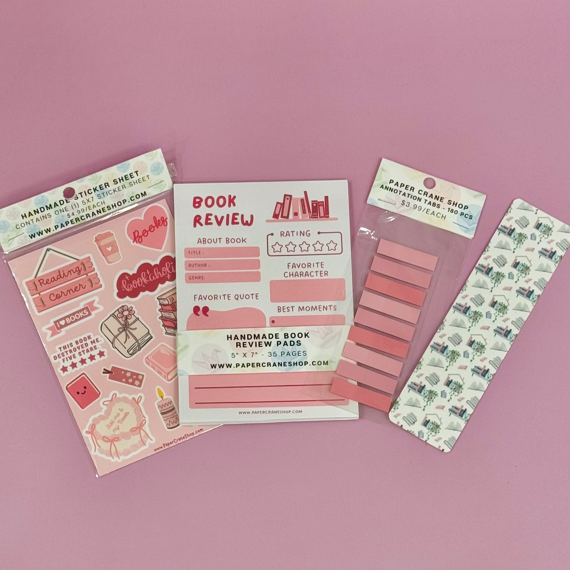Collection of stationery items including a book review sheet, stickers, and a bookmark on a pink background.