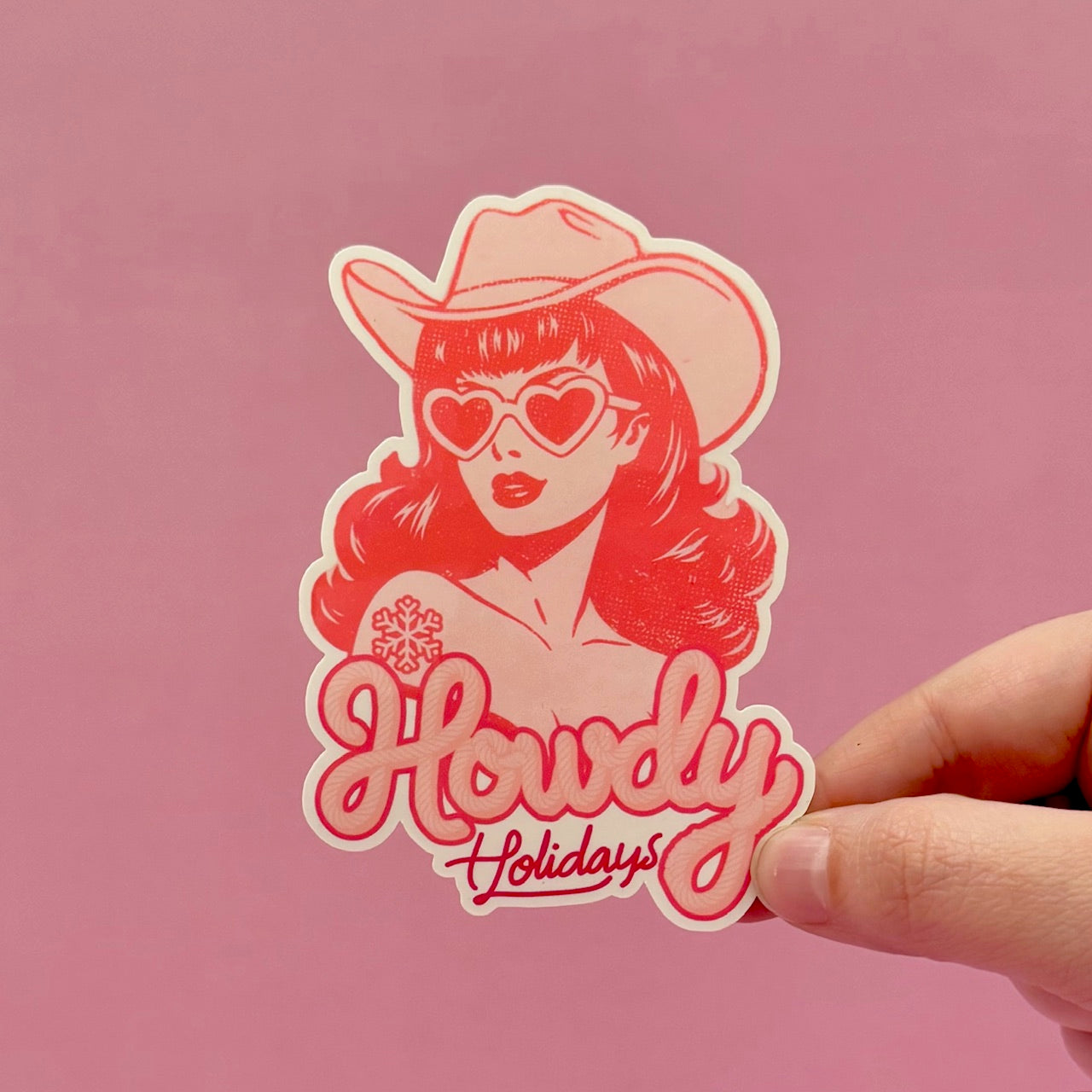 Sticker with a design of a woman in a cowboy hat and sunglasses with 'Howdy Holidays' text on a pink background.