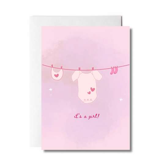 greeting card with baby clothes on a clothes lines that says "it's a girl"