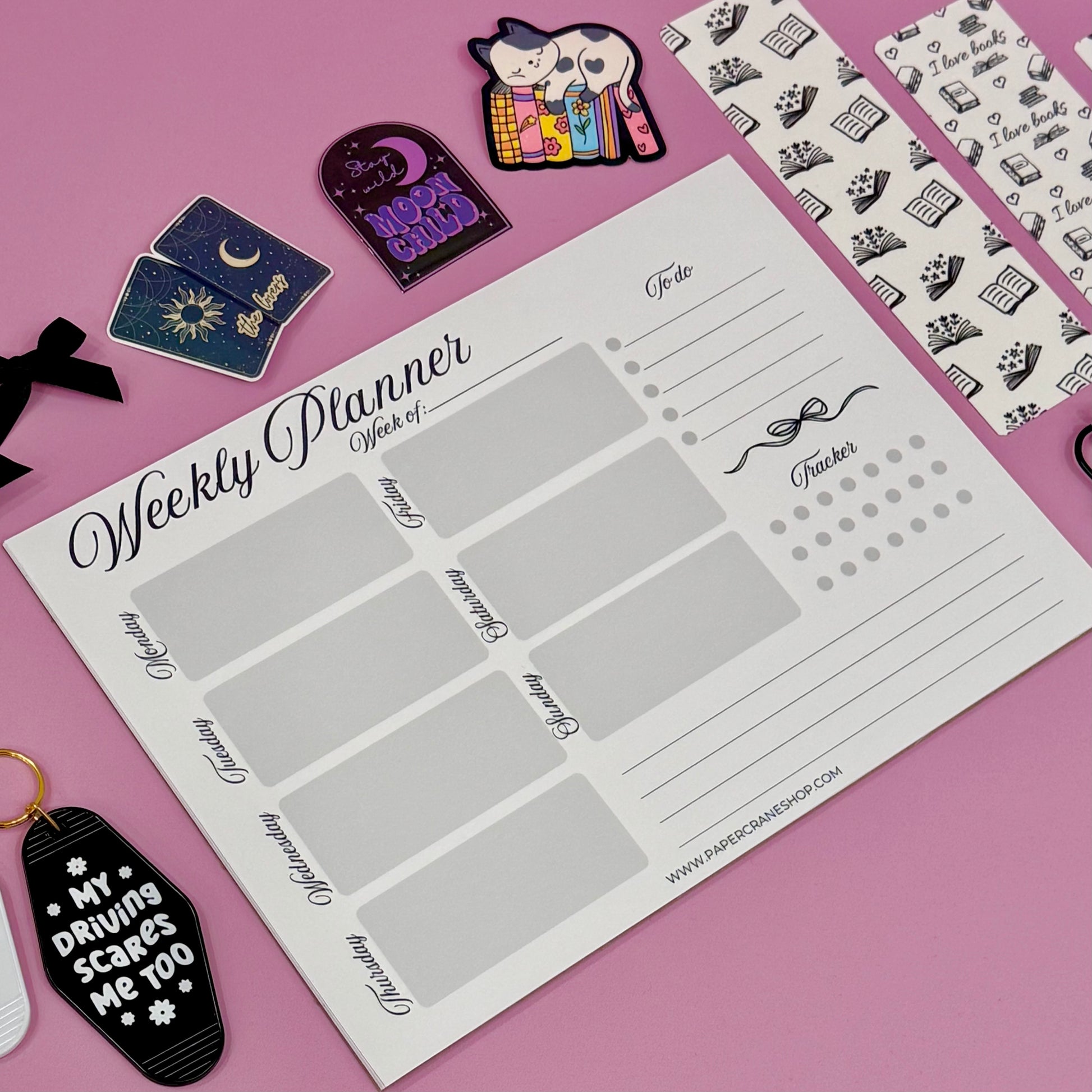Weekly planner sheet with decorative items on a pink background