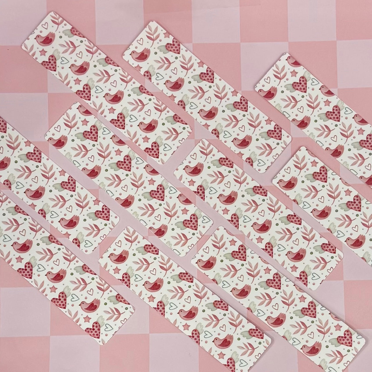 Set of patterned bookmarks with birds and hearts on a pink checkered background