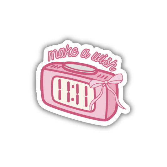 Pink alarm clock sticker with 'make a wish' text on a white background