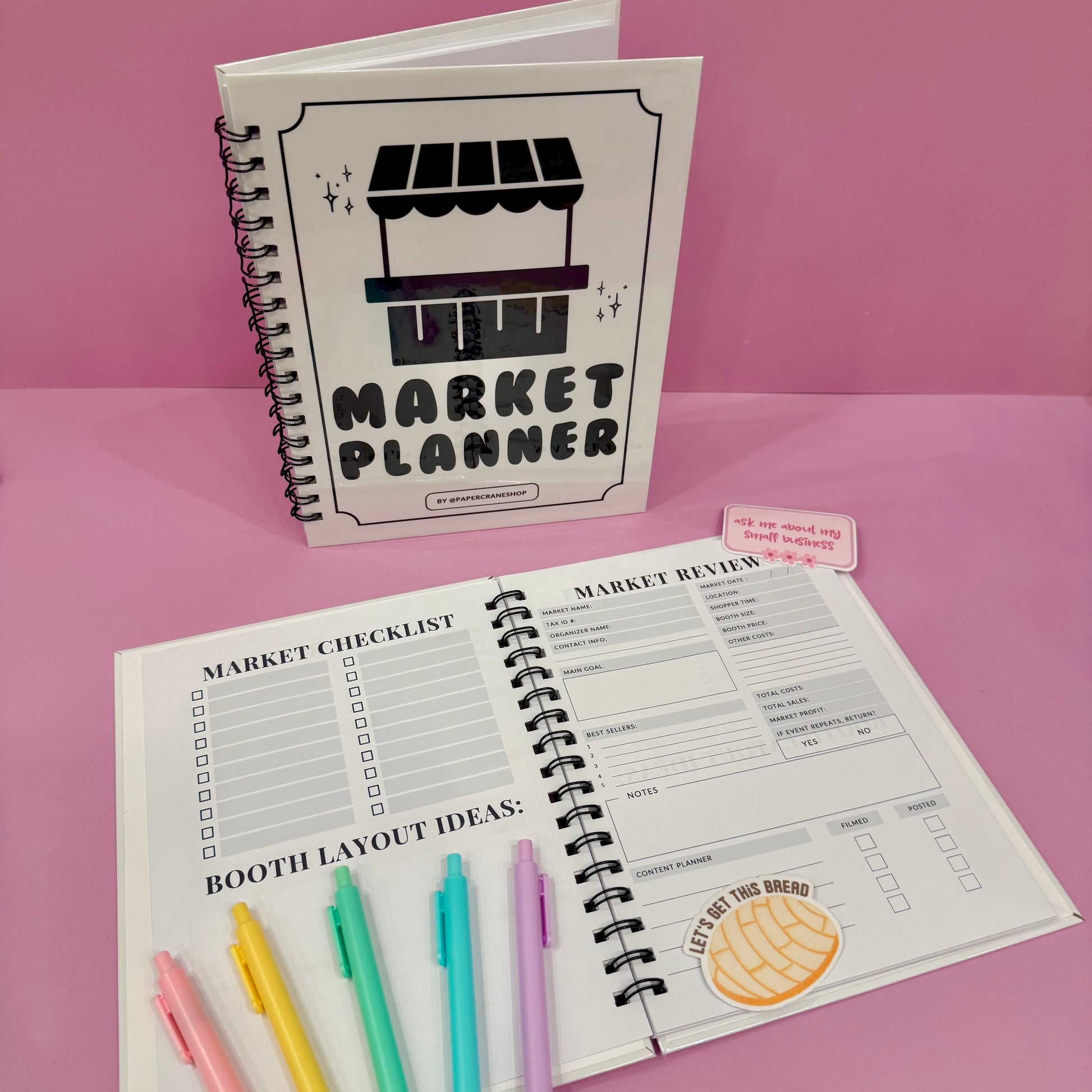Market Planner notebook with open pages on a pink background