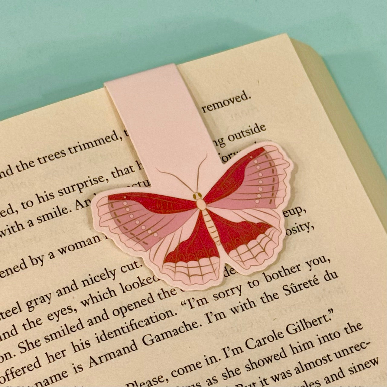 Moth-shaped pink bookmark on a book with a light blue background