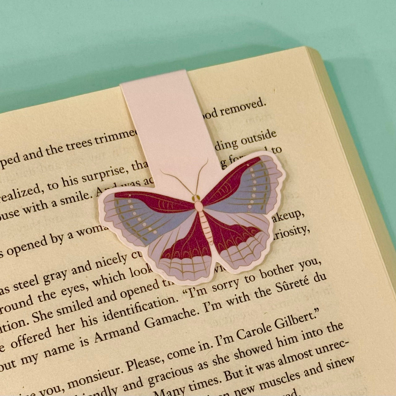 moth-shaped bookmark on a book with a light blue background