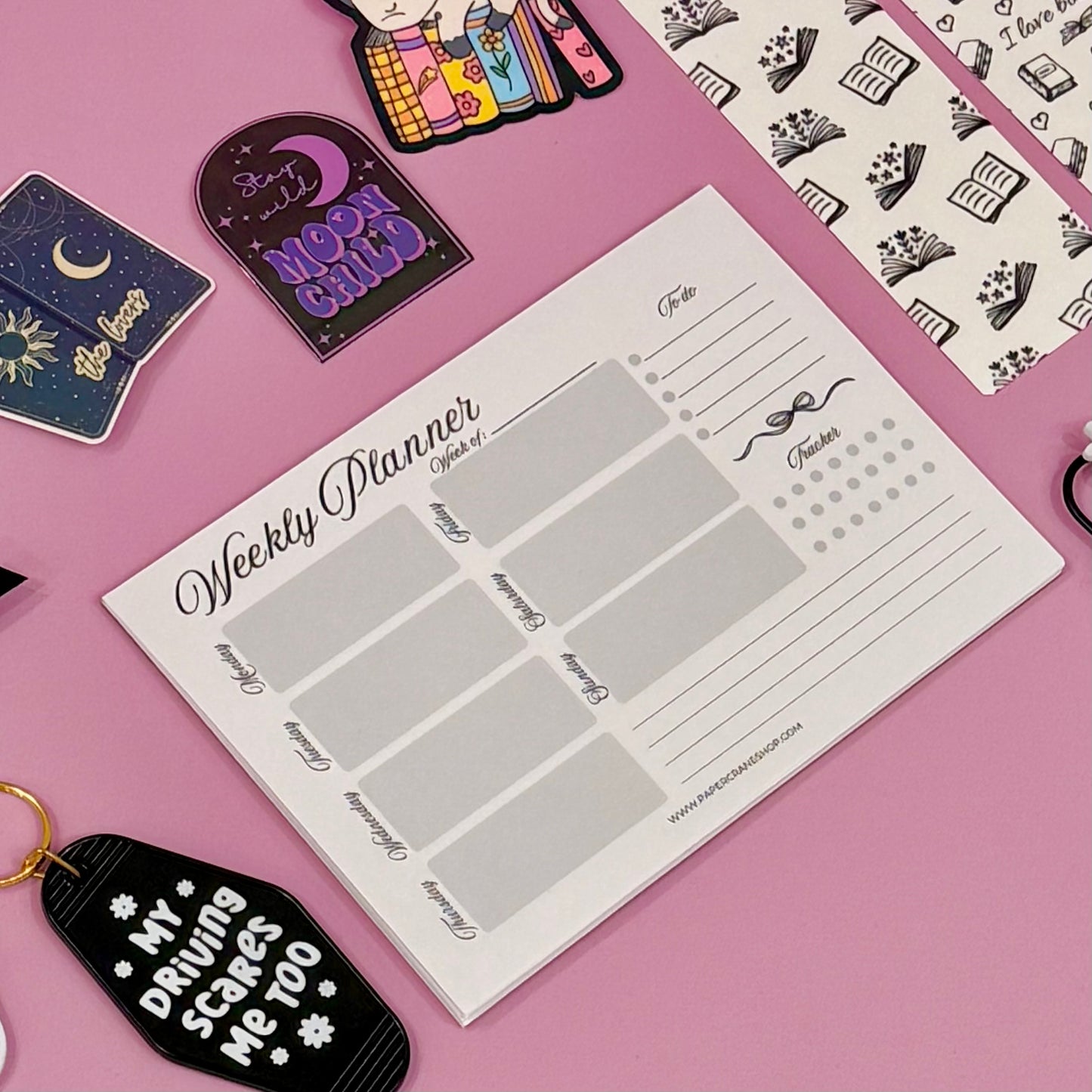 Weekly planner sheet on a pink background with decorative items