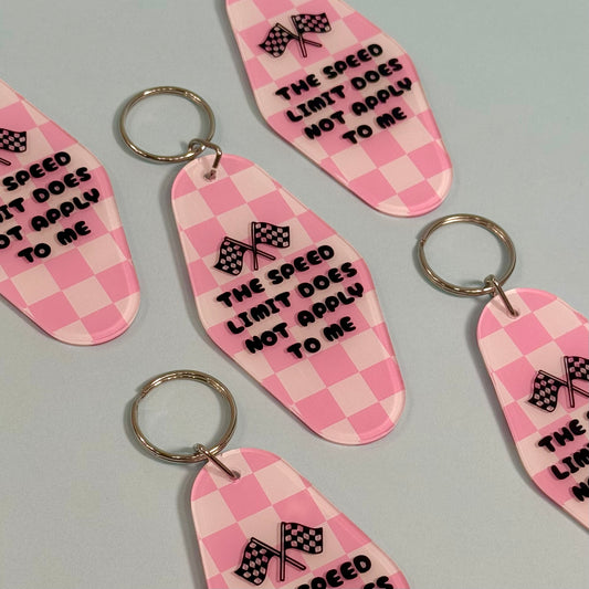 Pink checkered keychains with text and racing flags on a gray background
