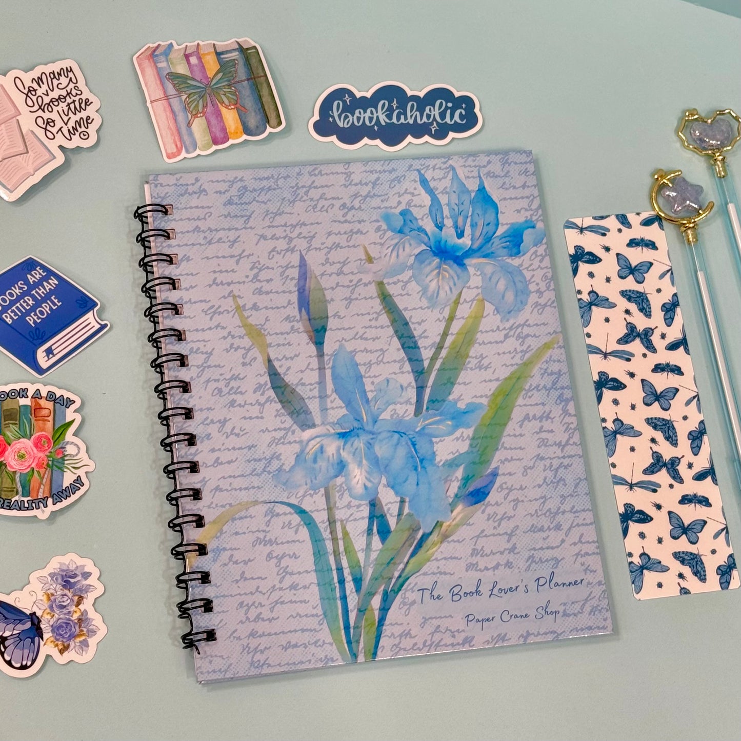 Notebook with floral design surrounded by decorative items on a light gray background