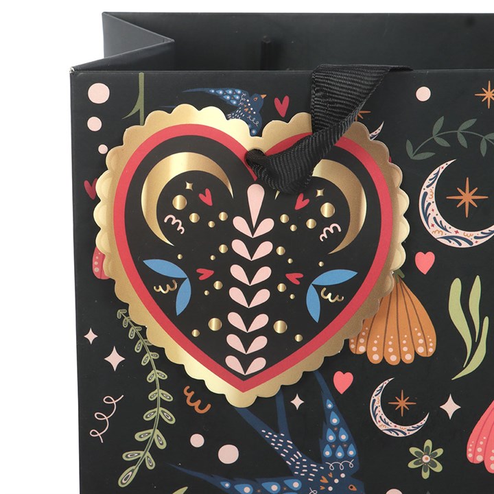 Decorative gift bag with a heart-shaped design and colorful patterns on a black background.