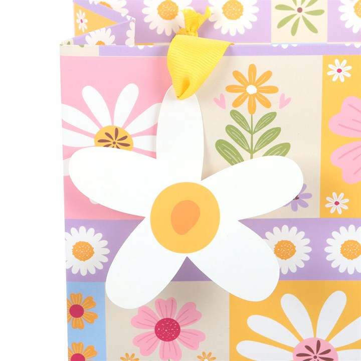 Colorful floral patterned gift bag with daisies and other flowers on a checkered background